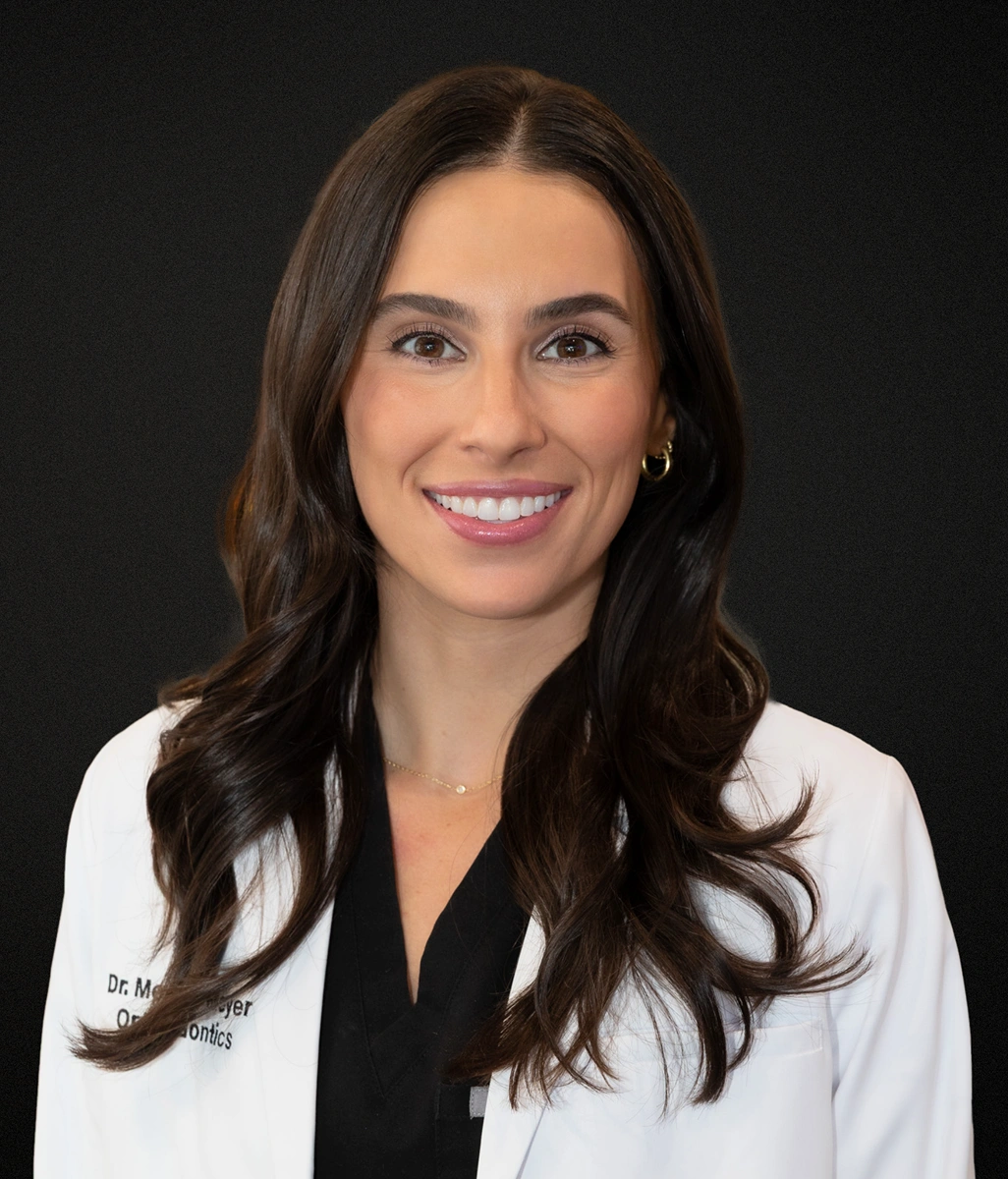 Professional headshot of smiling woman in white coat against dark background, Walnut Central Orthodontics staff member.