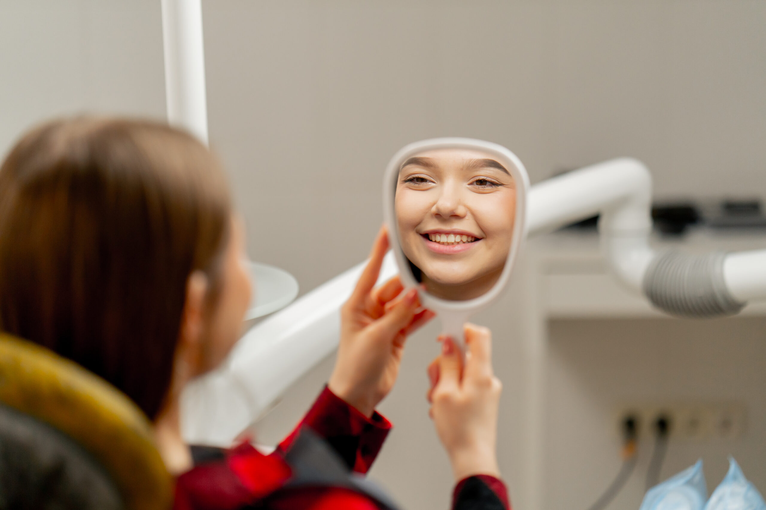 Young patient smiling in a dental mirror during an orthodontic consultation with a specialist